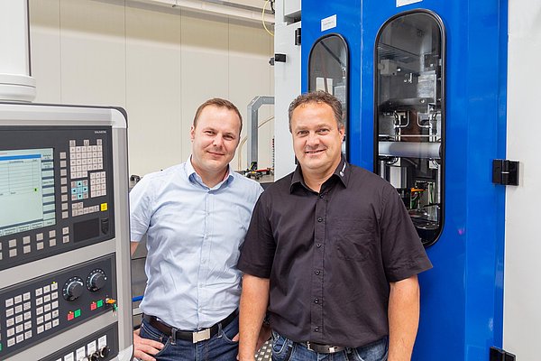 Stephan Otto, representante comercial de Blum-Novotest, y Markus Noack, ingeniero de desarrollo de Strama-MPS, frente al sistema de mecanizado especializado para levas.